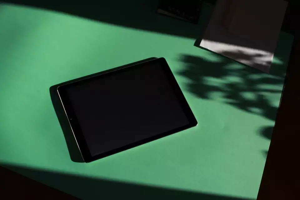 Screenshot eines schwarzen, rechteckigen Tablet-Computers auf einer grünen Fläche