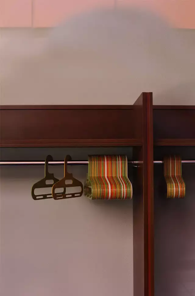 Das Foto zeigt eine braune Garderobe mit bunten leeren Plastik-Kleiderbügeln