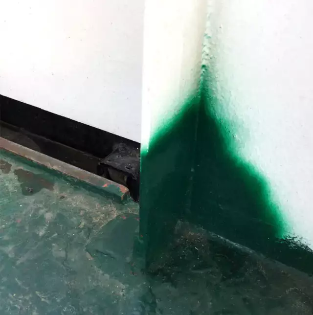 Das Foto zeigt eine grünen Farbklecks an einer Ecke von einer Wand
