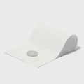 Weiße Kunststofffolie mit einem silbernen, kreisförmigen Gegenstand auf der linken Seite und einer grauen, gebogenen Form auf der rechten Seite, die die Flexibilität des Materials demonstriert.