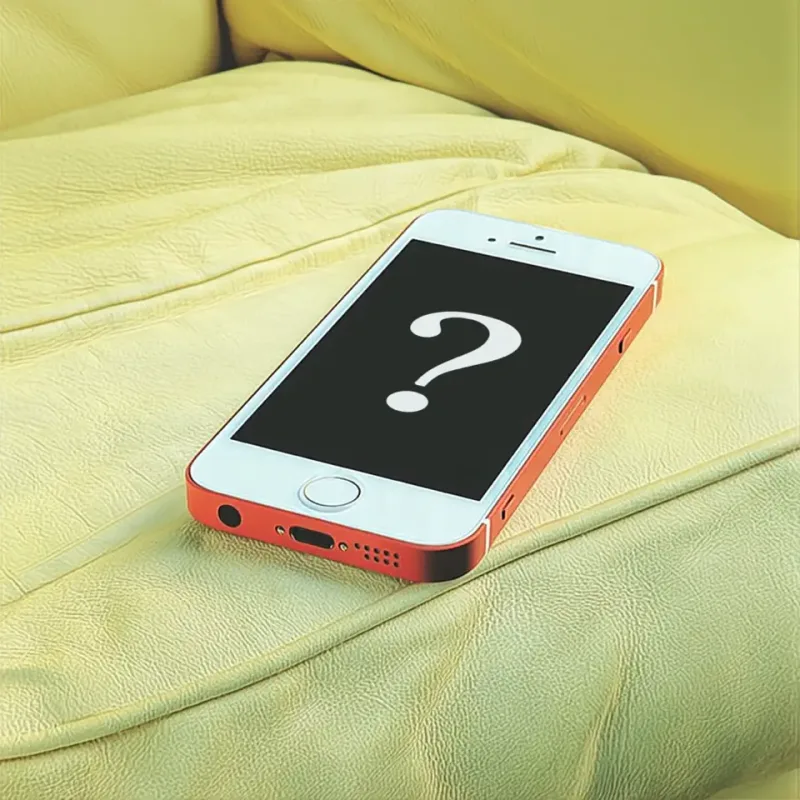 Ein rot-weißes Smartphone liegt auf gelbem Stoff und zeigt ein Fragezeichen auf dem schwarzen Bildschirm.