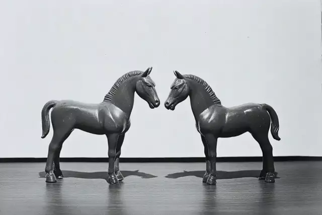 Two toy plastic horses with entire body positioned symmetrically face to face