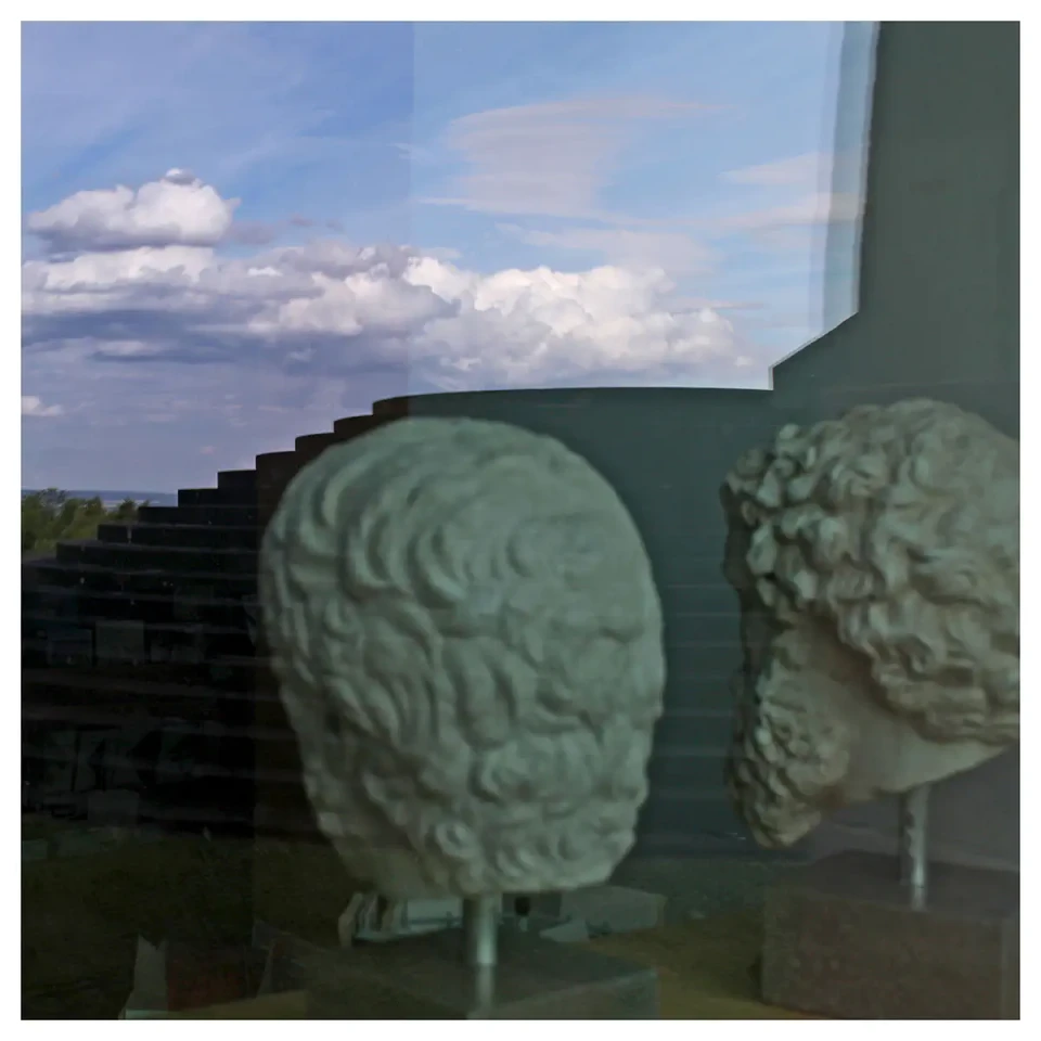 2 Gipsköpfe griechischer Philosophen in einer Museumsvitrine, die Köpfe stecken auf Metallstangen