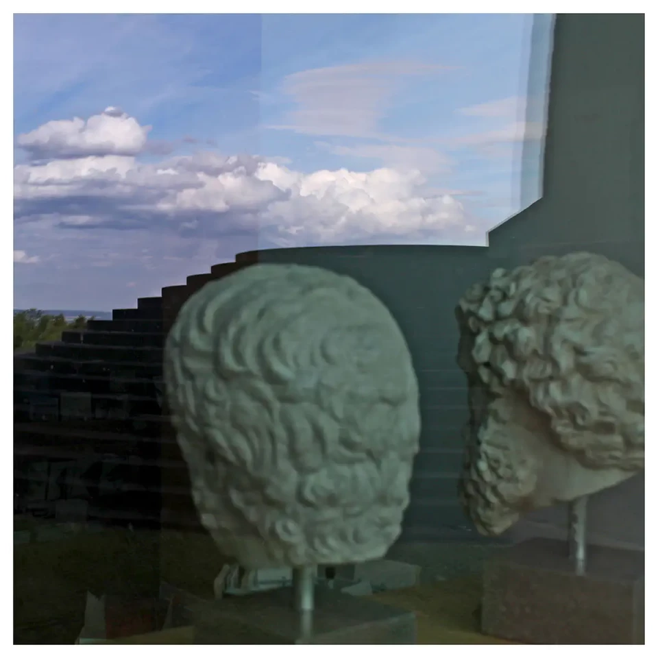 2 Gipsköpfe griechischer Philosophen in einer Museumsvitrine, die Köpfe stecken auf Metallstangen