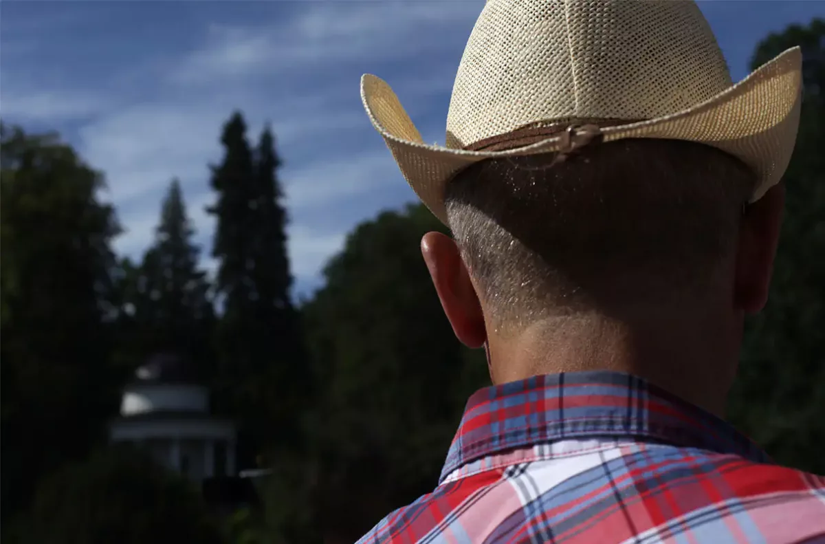 ein Mann in einem karierten Hemd, von hinten aufgenommen, mit einen Cowboy-Hut