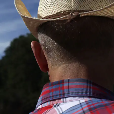 ein Mann in einem karierten Hemd, von hinten aufgenommen, mit einen Cowboy-Hut