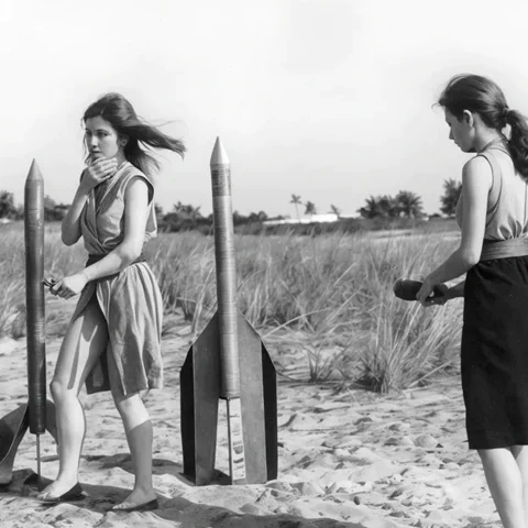 Zwei junge Frauen - Raketenmädchen - hantieren mit Holzraketen.