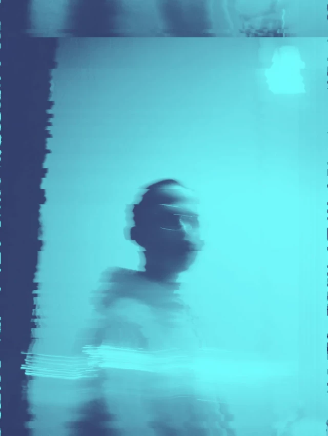 Ein Mann sitzt in türkisblauem Wasser, sein Gesicht und Oberkörper sind sichtbar. Das Foto hat eine körnige, verwaschene Qualität mit Farbverlagerungen. Die Aufnahme wirkt wie ein verblasstes oder fehlerhaft verarbeitetes Polaroid.
