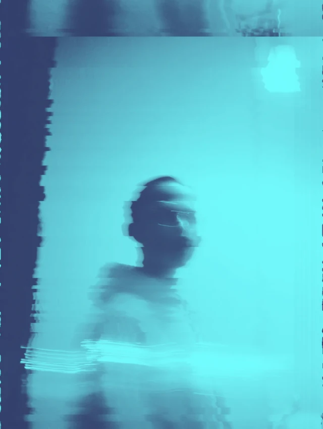 Ein Mann sitzt in türkisblauem Wasser, sein Gesicht und Oberkörper sind sichtbar. Das Foto hat eine körnige, verwaschene Qualität mit Farbverlagerungen. Die Aufnahme wirkt wie ein verblasstes oder fehlerhaft verarbeitetes Polaroid.