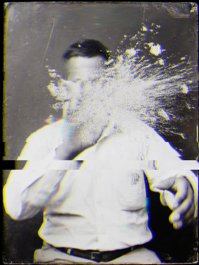 Ein Mann in weißem Hemd blickt nach unten, mit digitalen Verzerrungseffekten und pixeligen Fragmenten um seinen Kopf und Oberkörper. Das Schwarz-Weiß-Bild mit blauen und gelben Farbakzenten wirkt wie eine beschädigte oder bewusst verfremdet digitale Fotografie.
