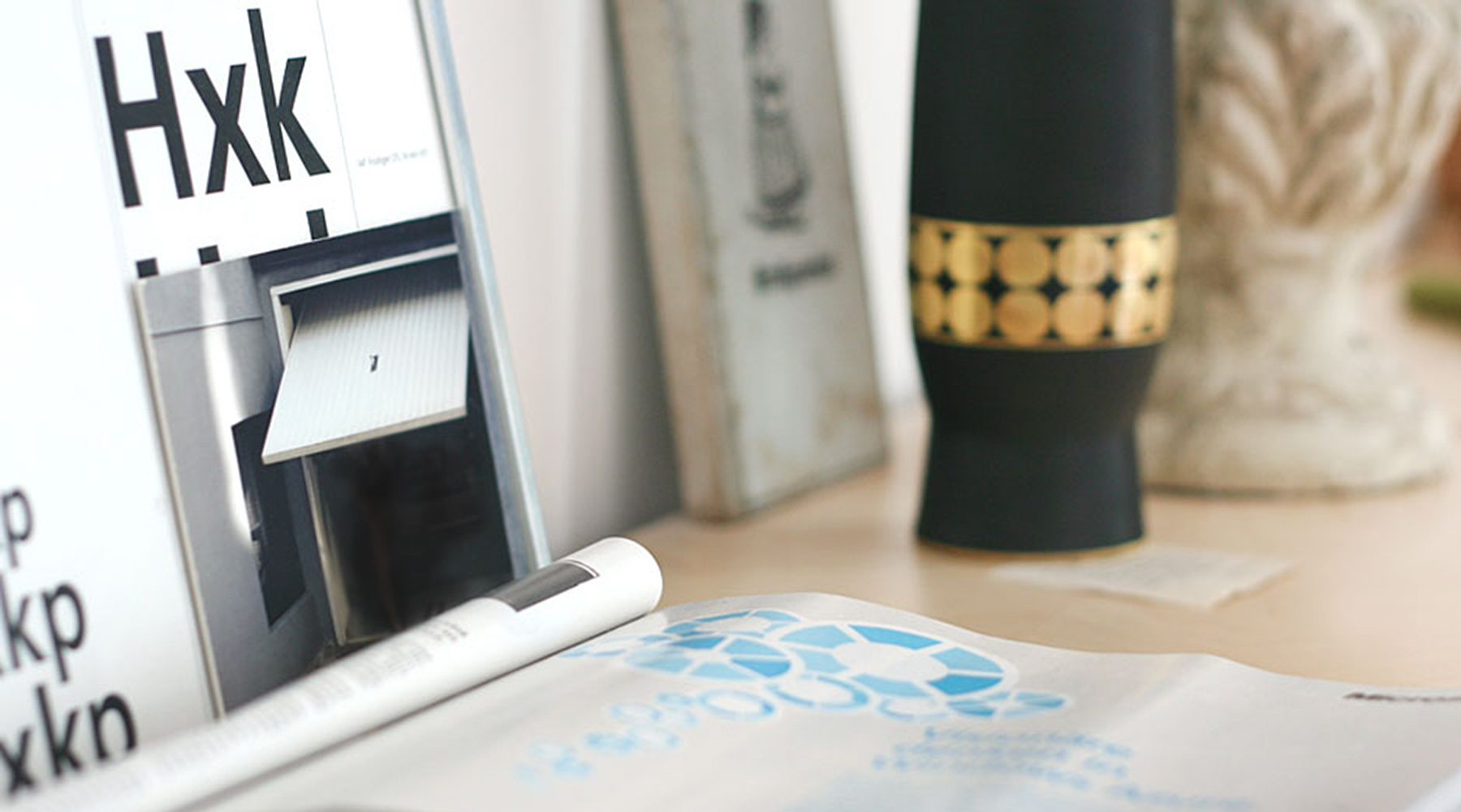 Innenansicht Agentur, Fotografie mit Garagentor auf einem Bücherregal, Vase, Buch und ein Barock Gips Ornament.