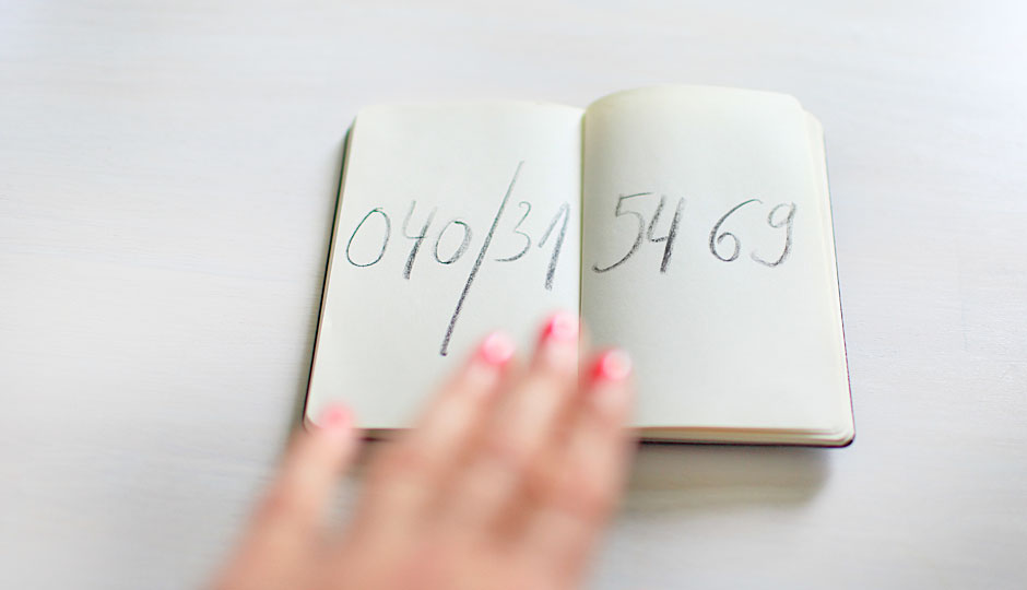 Aufgeschlagenes Notizheft mit der Telefonnummer von IconScreen: 040 315469; eine Frauenhand liegt auf dem Notizheft.