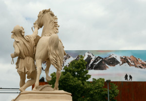 Pferd und Reiter Statue auf dem Hamburger Dom, im Hintergrund ein gemates Alpenpanorama
